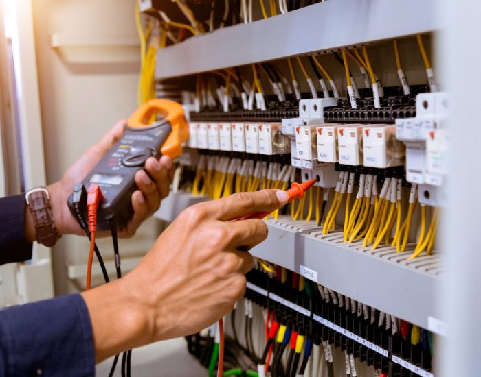 man-working-escalator Electrician measurements with multimeter testing current electric in control panel.